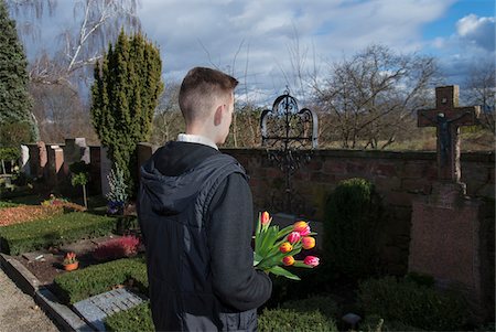 desconsolado - Teenager with Tulips Standing in front of Grave Stones in Cemetery Foto de stock - Sin royalties Premium, Código: 600-07351353
