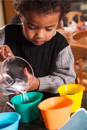 Boy Pouring Water into Dye Cups for Coloring Easter Eggs Foto de stock - Sin royalties Premium, Código: 600-07368549