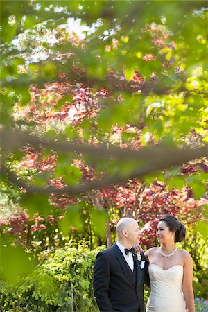 simsearch:700-07199871,k - Portrait of bride and groom smiling and looking at each other, standing in garden, Toronto, Ontario, Canada Foto de stock - Sin royalties Premium, Código: 600-07434946