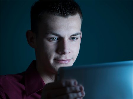 portrait close up dark background - Young Man looking at Tablet Computer, Studio Shot Stock Photo - Premium Royalty-Free, Code: 600-07431250