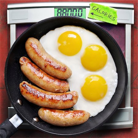 Overhead View of Greasy Fried Eggs and Sausage in Frying Pan with Scale Stock Photo - Premium Royalty-Free, Code: 600-07487381