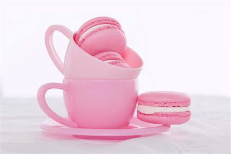 Pink macarons with pink teacups and saucers, studio shot on white background Stock Photo - Premium Royalty-Free, Code: 600-07487661