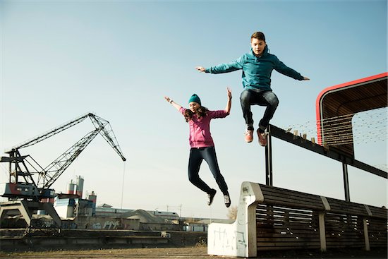 Teenage girl and boy jumping over bench outdoors, industrial area, Mannheim, Germany Stock Photo - Premium Royalty-Free, Artist: Uwe Umstätter, Image code: 600-07584772