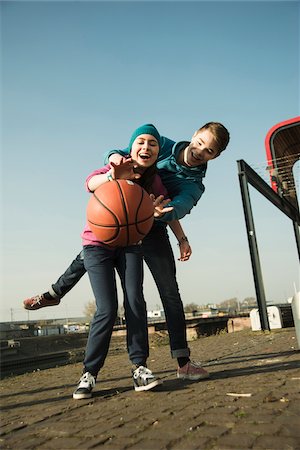 Teenage boy and girl playing basketball outdoors, industrial area, Mannheilm, Germany Stock Photo - Premium Royalty-Free, Code: 600-07584773