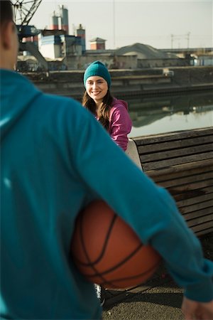 simsearch:600-06355195,k - Teenage girl outdoors wearing toque, smiling and looking at teenage boy holding basketball, industrial area, Mannheim, Germany Photographie de stock - Premium Libres de Droits, Code: 600-07584780