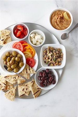 Overhead View of Appetizers, Chickpea Salad, Feta, Cherry and Sliced Tomatoes, Green and Black Olives, Hummus, and Grilled Pita Stock Photo - Premium Royalty-Free, Code: 600-07784040