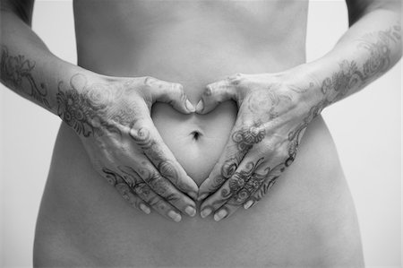 Close-up of Woman with Henna on Hands, Hands in Heart-shape around Belly Button, Studio Shot Stock Photo - Premium Royalty-Free, Code: 600-07784159