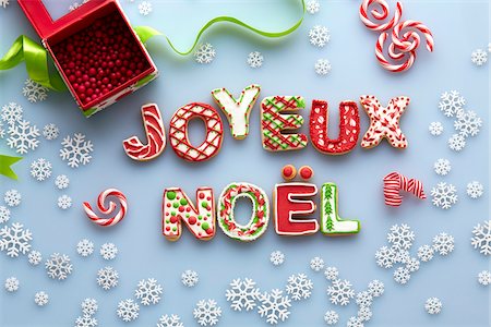 simsearch:700-03229755,k - Overhead View of Christmas Sugar Cookies spelling JOYEUX NOEL on Blue Background with Snowflakes Stock Photo - Premium Royalty-Free, Code: 600-07784431