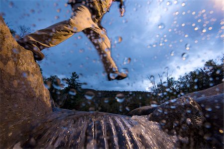 Low angle view of man jumping over a stream while hiking in New Hampshire, USA Foto de stock - Sin royalties Premium, Código: 600-07945091