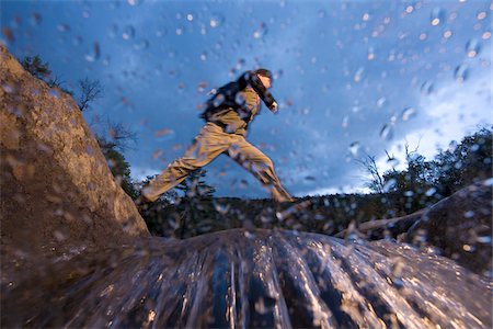 pisando - Low angle view of man jumping across river while hiking in New Hampshire, USA Foto de stock - Sin royalties Premium, Código: 600-07945092