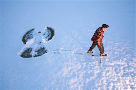 An elderly man using a cane in the snow, walking away from a snow angel, New England, USA Stock Photo - Premium Royalty-Free, Code: 600-07945119