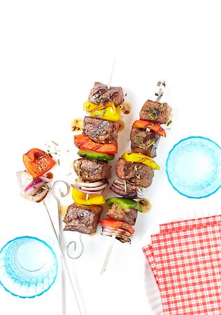 Grilled Beef and Vegetable Skewers with turquoise drinking glasses and red and white checkered napkins, studio shot on white background Stockbilder - Premium RF Lizenzfrei, Bildnummer: 600-08002081