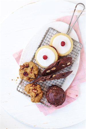 Variety of healthy cookies on a wire cooling rack with a white, cutting board and a pink napkin, studio shot on white background Stock Photo - Premium Royalty-Free, Code: 600-08002097