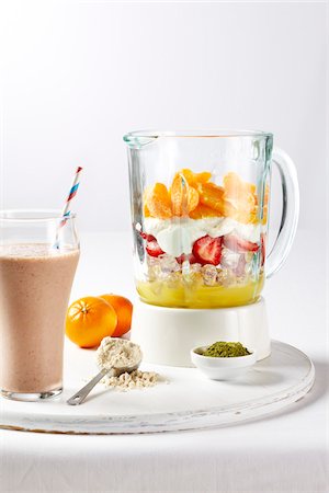 simsearch:600-06935002,k - Protein fruit shake ingredients in a blender with full glass and straw on a white cutting board, studio shot on white background Stock Photo - Premium Royalty-Free, Code: 600-08002116
