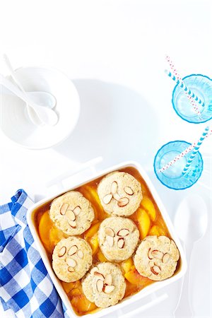 peach - Peach almond cobbler with blue checkered napkin and blue cups with straws, studio shot on white background Stock Photo - Premium Royalty-Free, Code: 600-08002110