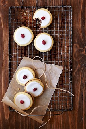 Sandwich cookies with icing and a cranberry on top, on a cooling rack, studio shot Stock Photo - Premium Royalty-Free, Code: 600-08002122