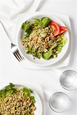 Two plates of baked tuna and rice on salad greens with tomato wedges, water glasses and a fork, studio shot on white background Stockbilder - Premium RF Lizenzfrei, Bildnummer: 600-08002131