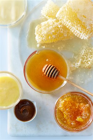 salsa - Overhead View of Small Glass Bowl with Raw Honey and Honey Dipper and Honey Combs on Tabletop with Bowls of Sweet Dips made with Honey Foto de stock - Sin royalties Premium, Código: 600-08002395