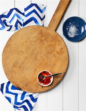 simsearch:600-06553474,k - Overhead View of Wooden Pizza Board with Bowl of Chili Sauce, Dish with Salt and Napkin Foto de stock - Sin royalties Premium, Código: 600-08060048