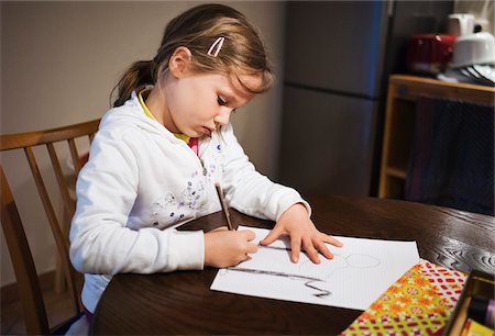 5 year old girl sitting at the table and drawing with a pencil, Germany Stock Photo - Premium Royalty-Free, Code: 600-08512535