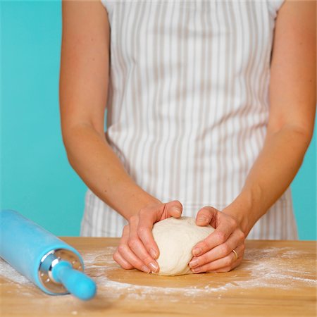 simsearch:600-06059753,k - Woman in Striped Apron Kneading Dough on Wooden Surface with Blue Rolling Pin Stock Photo - Premium Royalty-Free, Code: 600-08512612