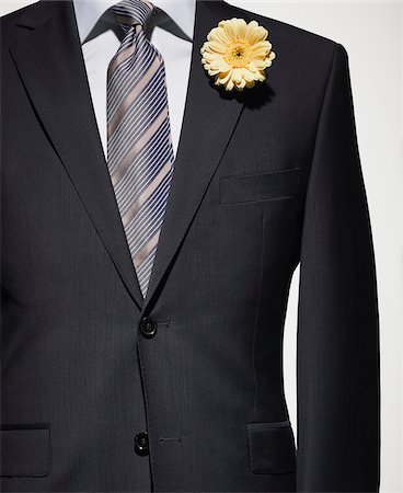 Detail of a dark blue suit jacket with grey shirt and striped necktie, and yellow flower Stock Photo - Premium Royalty-Free, Code: 600-08542885