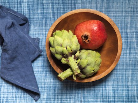 simsearch:600-07067667,k - Overhead View of Pomegranate and Artichokes in Wooden Bowl on Blue Tablecloth with Napkin Stock Photo - Premium Royalty-Free, Code: 600-08559828