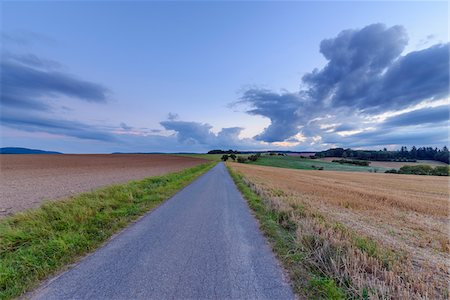 simsearch:700-07803094,k - Countryside with harvested cereal field and paved laneway at dusk in summer at Roellbach in Spessart hills in Bavaria, Germany Stock Photo - Premium Royalty-Free, Code: 600-08973334