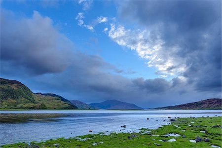 scottish - Grassy shoreline and hills with dramatic clouds at sunrise along the Scottish coast near Eilean Donan Castle and Kyle of Lochalsh in Scotland, United Kingdom Stock Photo - Premium Royalty-Free, Code: 600-08986488