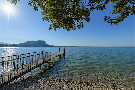 simsearch:600-09022419,k - Sun shining on Lake Garda (Lago di Gardo) with wooden jetty in the summer at Garda in Veneto, Italy Photographie de stock - Premium Libres de Droits, Code: 600-09022407