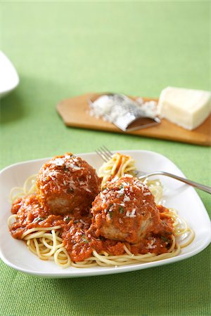 Spaghetti and meatballs with parmasean cheese in a red tomato sauce on a white plate with green linen tablecloth Stock Photo - Premium Royalty-Free, Code: 600-09119344