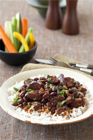 Black beans with sausage on rice served with raw vegetable sticks Photographie de stock - Premium Libres de Droits, Code: 600-09119351