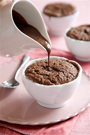 simsearch:600-09119330,k - Individual chocolate souffle with chocolate sauce poured on top on a pink background Stock Photo - Premium Royalty-Free, Code: 600-09119379