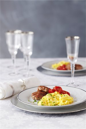 simsearch:600-06961849,k - Brunch setting with scrambled eggs, sausage patties, grilled tomatoes and champagne glasses Foto de stock - Sin royalties Premium, Código: 600-09119394