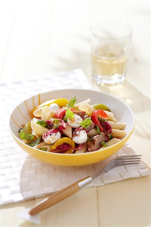 simsearch:600-07156166,k - Pasta salad with mozzarella cheese, peppers, raddichio, sausage and basil in a yellow bowl with a glass of white wine and a fork Foto de stock - Sin royalties Premium, Código: 600-09119397