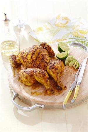 Spatchcock grilled chicken with spice rub on wooden cutting board and lime wedges Stock Photo - Premium Royalty-Free, Code: 600-09119392