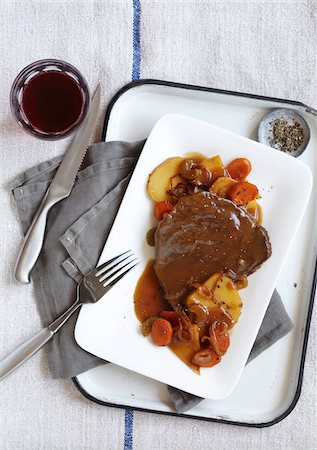 Steak with gravy served with potatoes, carrots and onions and a glass of red wine Stock Photo - Premium Royalty-Free, Code: 600-09119430