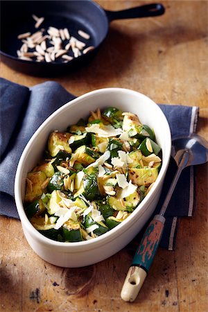 Roasted zucchini with shaved parmesan cheese and slivered toasted almonds in an oval serving dish Photographie de stock - Premium Libres de Droits, Code: 600-09119488