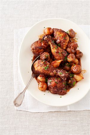 Chicken with wine sauce (Coq Au Vin) on a white platter with serving spoon Photographie de stock - Premium Libres de Droits, Code: 600-09155506