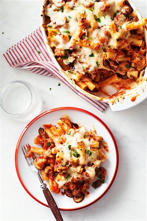 simsearch:600-07156166,k - Baked ziti with mushrooms in a casserole dish with a portion on a plate with a fork in front Foto de stock - Sin royalties Premium, Código: 600-09155530