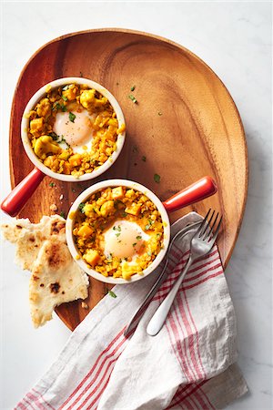 Two ramekins with lentil curry and baked eggs with naan bread on a wooden serving platter Photographie de stock - Premium Libres de Droits, Code: 600-09155542