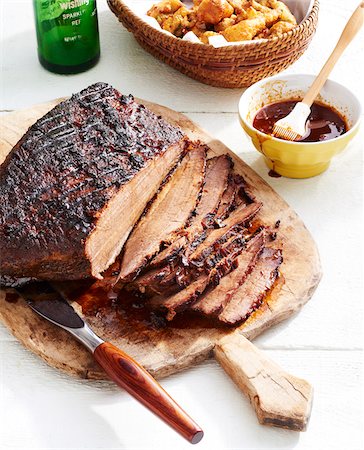 simsearch:600-09155593,k - Sliced BBQ beef brisket with a bowl of barbeque sauce and a baslket of deep fried okra in the background Stock Photo - Premium Royalty-Free, Code: 600-09155553