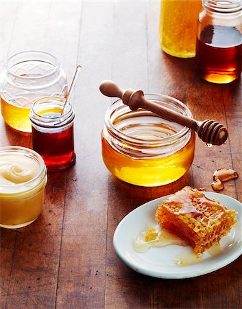 Still life of honey jars with honeycomb and wooden, honey dipper Stock Photo - Premium Royalty-Free, Code: 600-09159790
