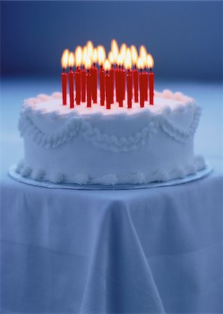 Cake with Lit Candles on Corner Of Table Foto de stock - Sin royalties Premium, Código: 600-00056887