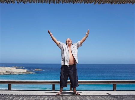 fat 60 year old man - Man Standing by the Beach, Arms Raised in the Air Foto de stock - Sin royalties Premium, Código: 600-00796364