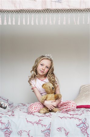 Girl Sitting on Bed, Holding Teddy Bear and Wearing Tiara Stock Photo - Premium Royalty-Free, Code: 600-00823701