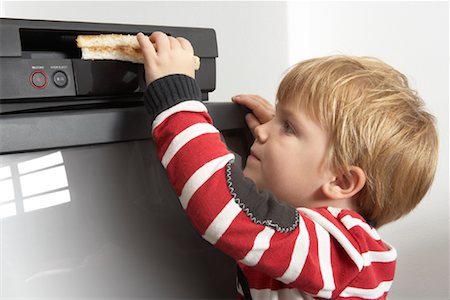 simsearch:600-00848628,k - Boy Putting Sandwich in VCR Fotografie stock - Premium Royalty-Free, Codice: 600-00848637