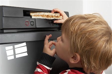 simsearch:600-00848628,k - Boy Putting Sandwich in VCR Fotografie stock - Premium Royalty-Free, Codice: 600-00848638