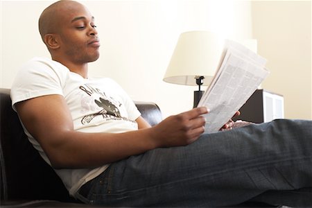 relaxing in couch black male - Man Reading Newspaper at Home Stock Photo - Premium Royalty-Free, Code: 600-00934264