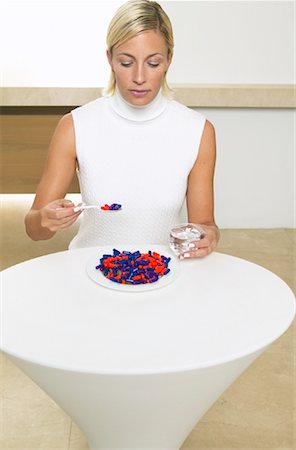 Woman Sitting at Table, Eating Meal of Pills Stock Photo - Premium Royalty-Free, Code: 600-00934642